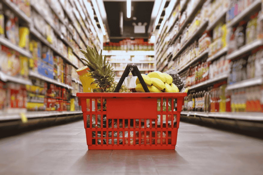 Canasta de supermercado con frutas y alimentos en el pasillo como ejemplo de compras del hogar planificadas