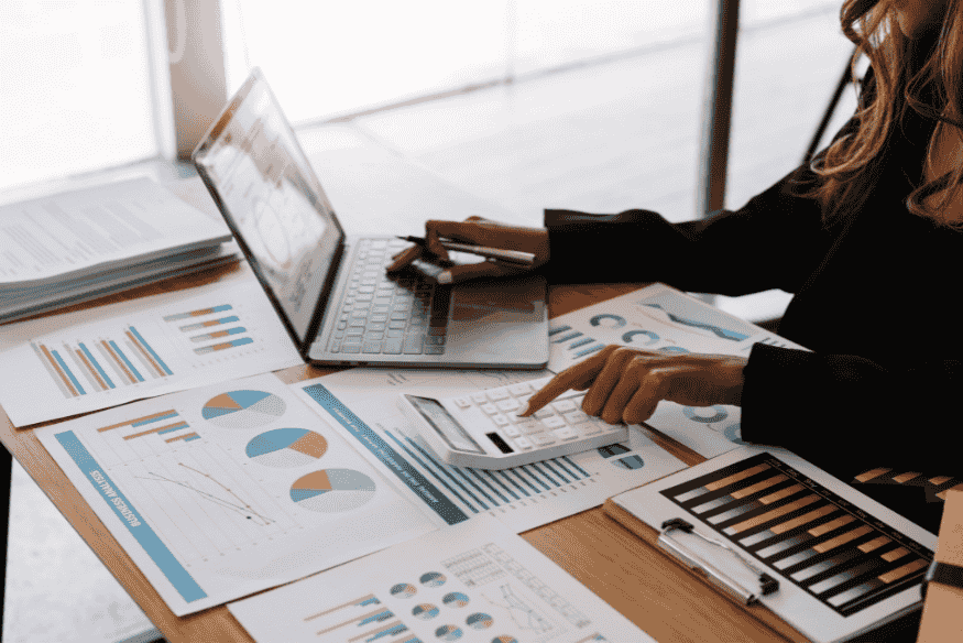 Análisis financiero con calculadora, laptop y gráficos para planificar compras grandes con tarjeta de crédito