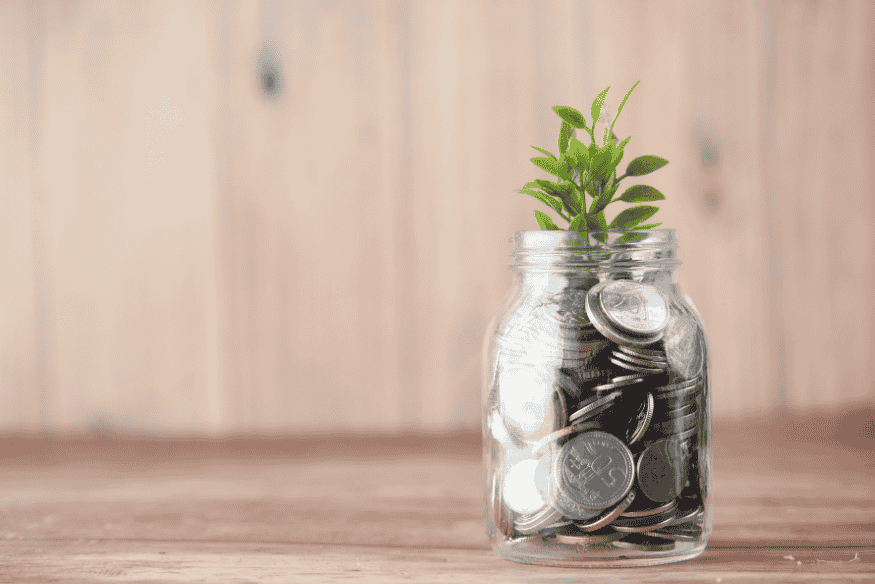 Frasco con monedas y una planta creciendo desde su interior.
