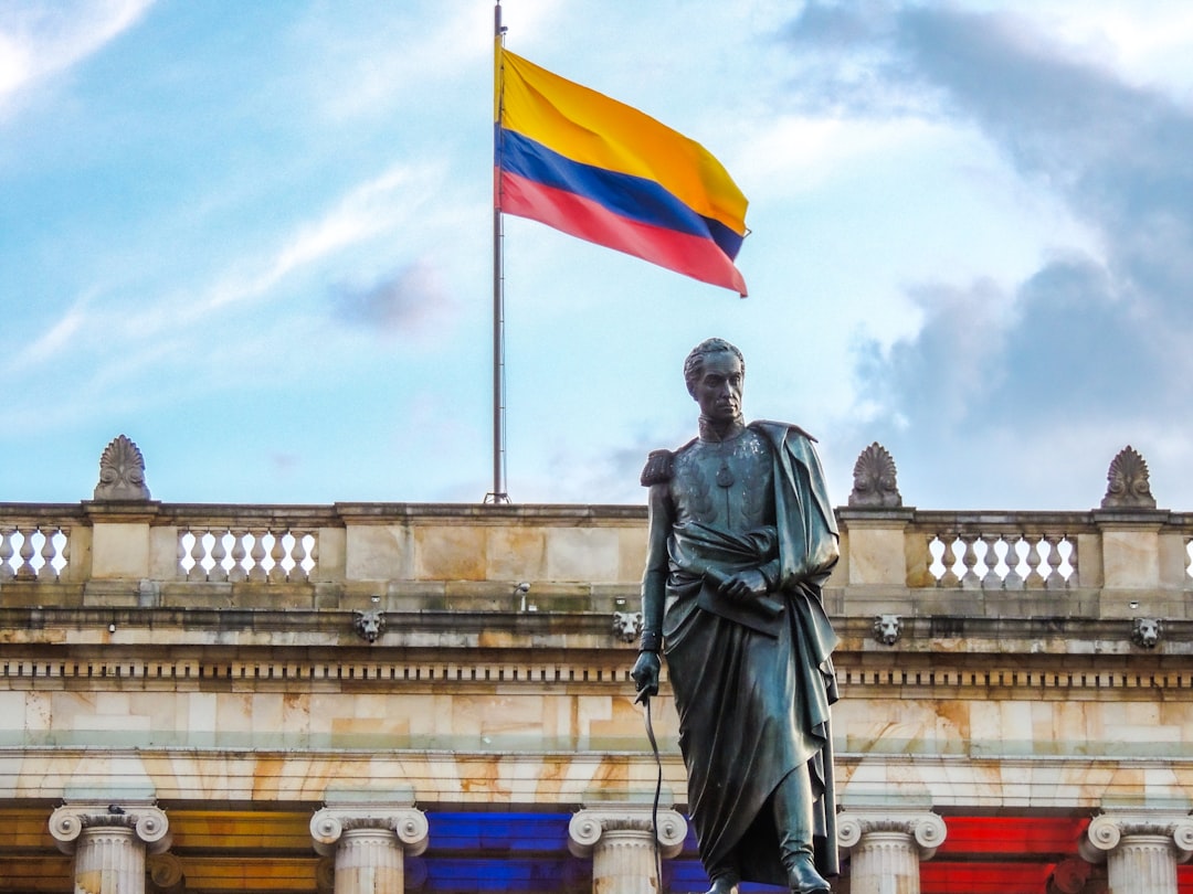 Colombian flag waves above a statue.